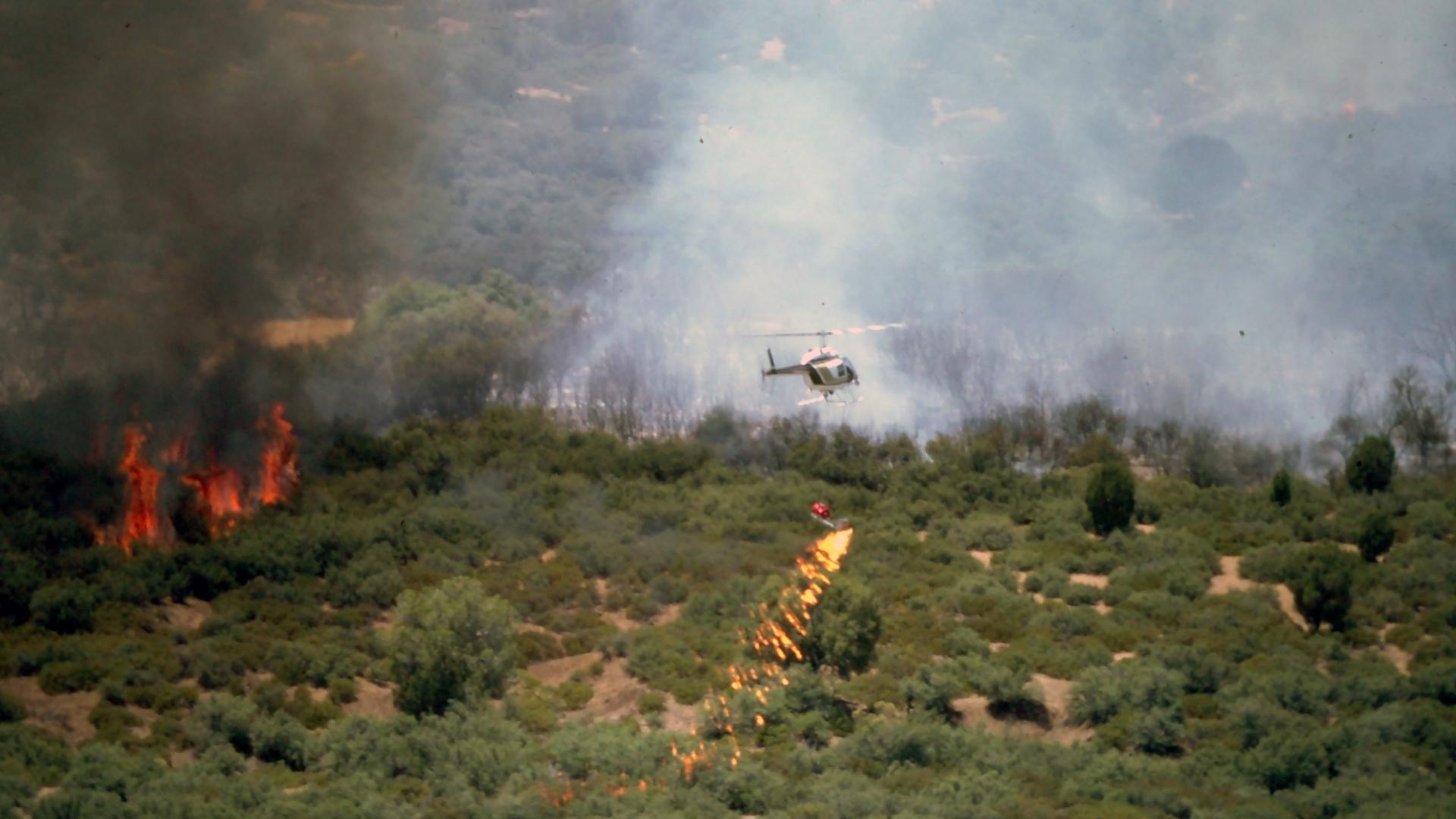 Helichopter dropping fire in brush land
