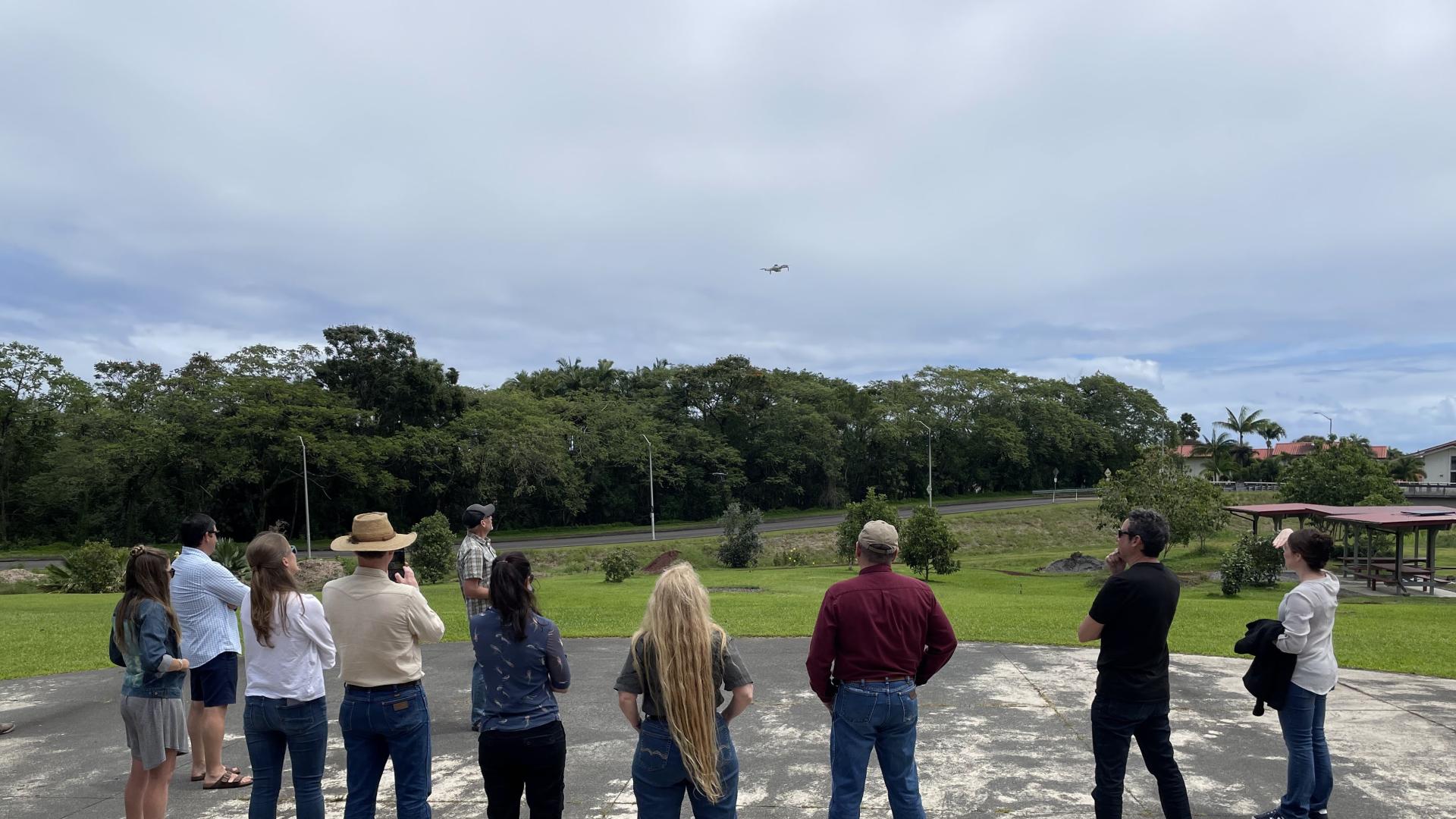 A group of people looking at a drone in the air